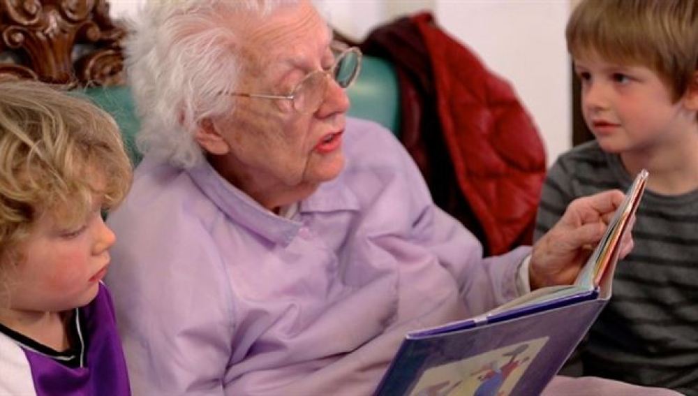 Una anciana leyéndole un cuento a dos niños
