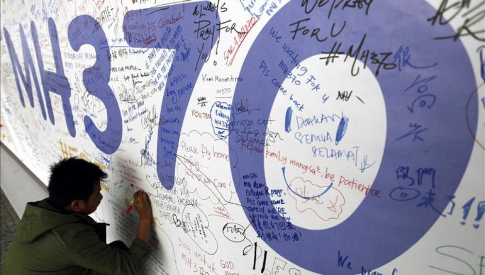 Un hombre escribiendo mensajes en honor a las víctimas del vuelo MH370 de Malaysia Airlines