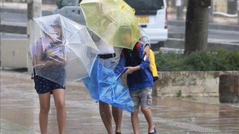 Varios viandantes luchan contra los fuertes vientos y la lluvia