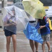 Varios viandantes luchan contra los fuertes vientos y la lluvia