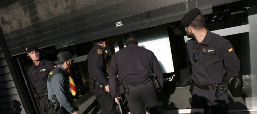 Agentes ante la fachada de la sede de CDC en Barcelona que esta siendo registrada Agentes ante la fachada de la sede de CDC en Barcelona que esta siendo registrada