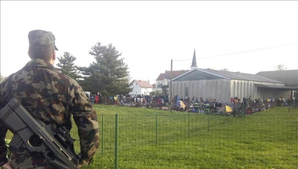Un soldado vigila a un grupo de refugiados en el campamento provisional de Dobova, Eslovenia