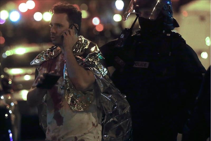 Un hombre ensangrentado habla por teléfono junto a un policía en el exterior de la discoteca Bataclan en París Un hombre ensangrentado habla por teléfono junto a un policía en el exterior de la discoteca Bataclan en París
