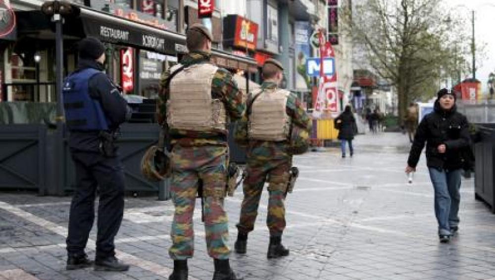 oficial de la policía belga junto a soldados patrullando la zona comercial en Bruselas 