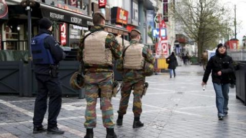 oficial de la polic&iacute;a belga junto a soldados patrullando la zona comercial en Bruselas 