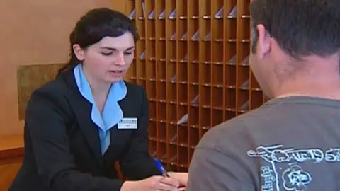 Una recepcionista atiende a un cliente Una recepcionista atiende a un cliente