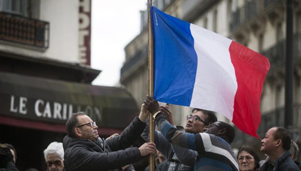 Varias personas sujetan una bandera de Francia