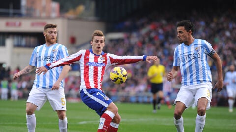 Griezmann controla el bal&oacute;n ante los defensores del M&aacute;laga