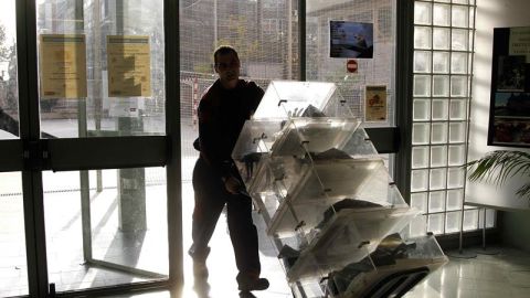Un trabajador de los almacenes municipales de Barcelona transporta varias urnas en el instituto Men&eacute;ndez y Pelayo, uno de los miles de colegios electorales donde los ciudadanos acudiran a votar en los comicios del pr&oacute;ximo domingo.