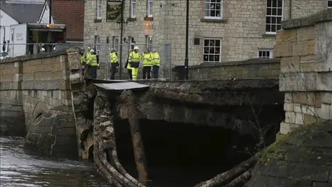 Miembros de los servicios de emergencias permanecen junto a un puente que se ha hundido debido a las fuertes lluvias en Tadcastle en Yorkshire Viviendas sin electricidad en Irlanda del Norte y Escocia por el temporal