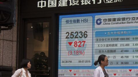  Dos mujeres pasan junto a una pantalla que muestra el &iacute;ndice de referencia Hang Seng en Hong Kon