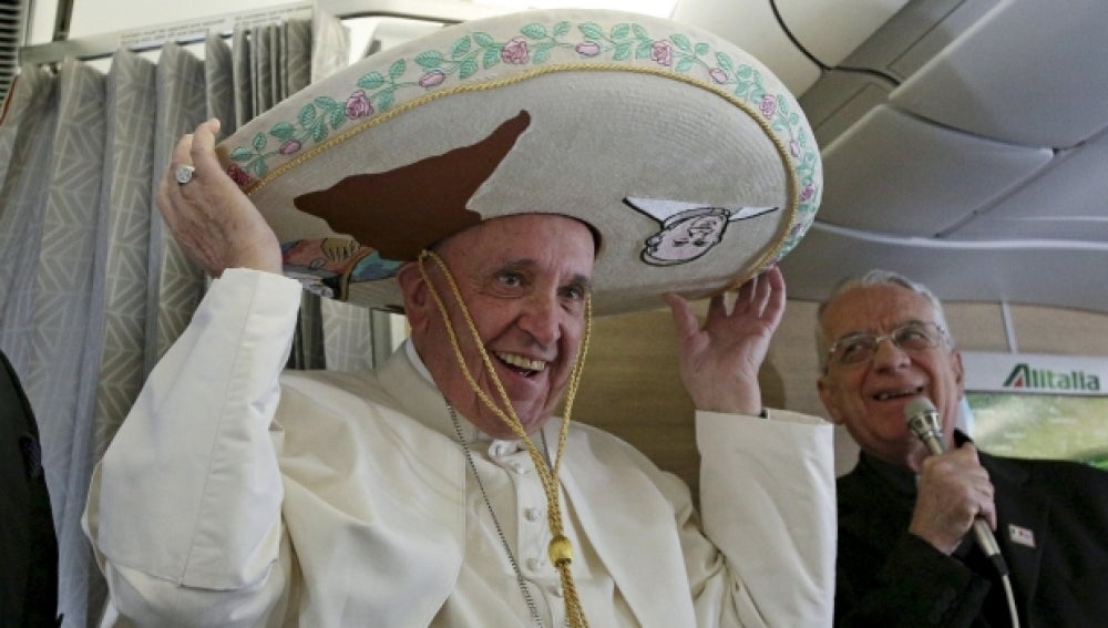 El Papa Francisco recibe un sombrero mexicano de parte de un periodista durante el vuelo