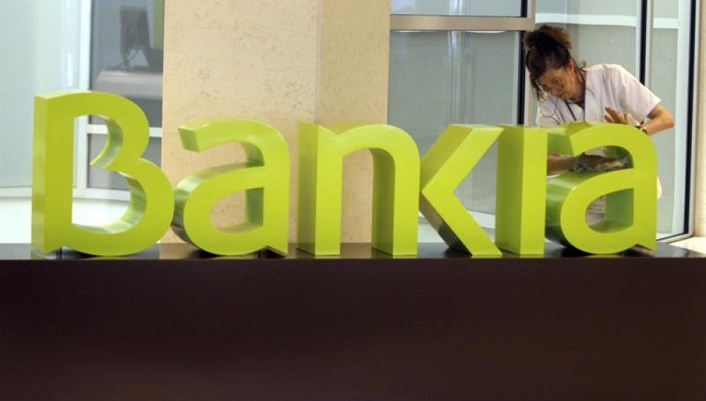 Una operaria limpia el logo de Bankia