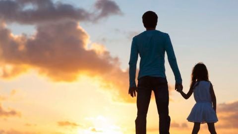 Un padre con su hija durante la puesta de sol