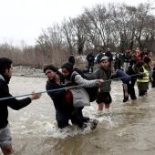 Refugiados usan una cuerda para cruzar el río en la frontera con Macedonia