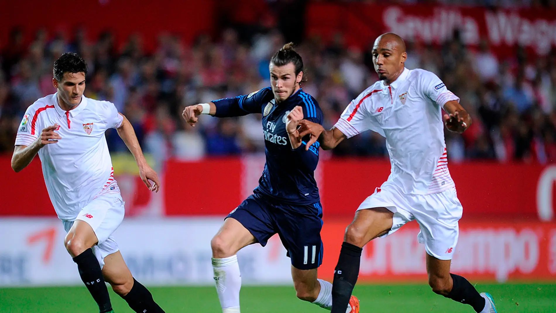 Bale entre dos jugadores sevillistas queriéndose hacerse con el balón. 