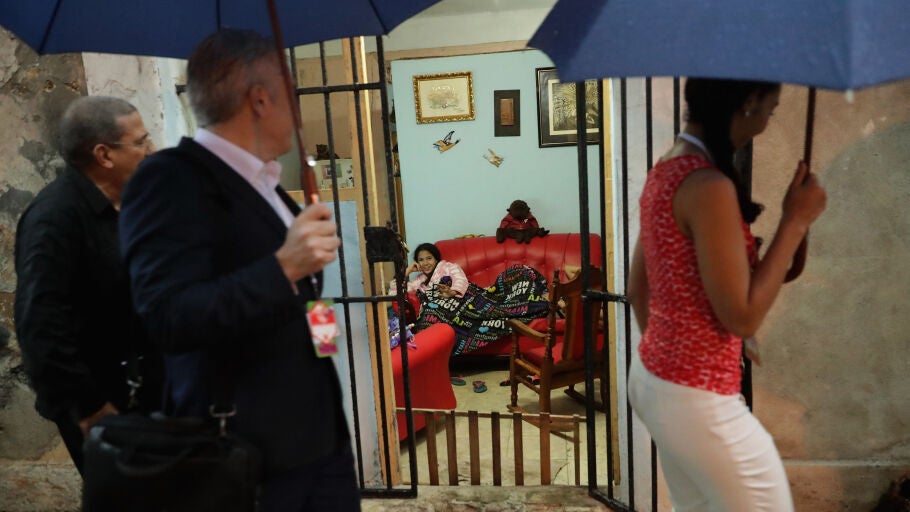 Una mujer ve la televisi&oacute;n en el sal&oacute;n de su casa mientras pasa la comitiva de Obama por la calle en La Habana