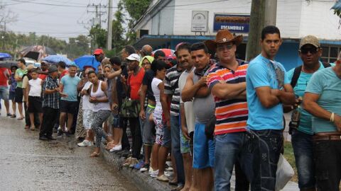 Un grupo de cubanos observa la llegada del presidente de los EEUU, Barack Obama.