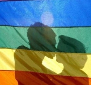 Dos jóvenes se besan tras la bandera LGTB Dos jóvenes se besan tras la bandera LGTB