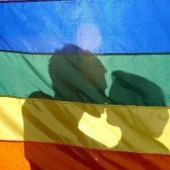 Dos jóvenes se besan tras la bandera LGTB