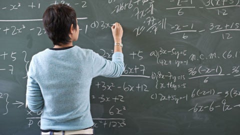 Imagen de una profesora escribiendo en la pizarra