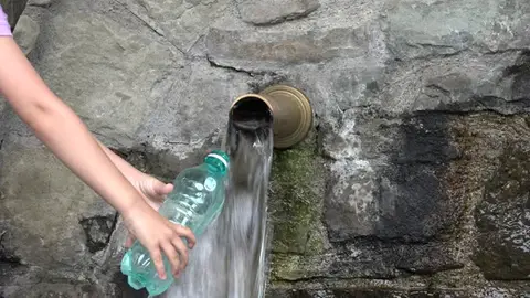 Imagen de una persona llenando una botella de agua Imagen de una persona llenando una botella de agua