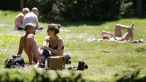 Varias personas toman el sol en el Parque del Retiro