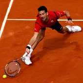 Novak Djokovic estirándose para alcanzar la pelota en Roland Garros Novak Djokovic estirándose para alcanzar la pelota en Roland Garros