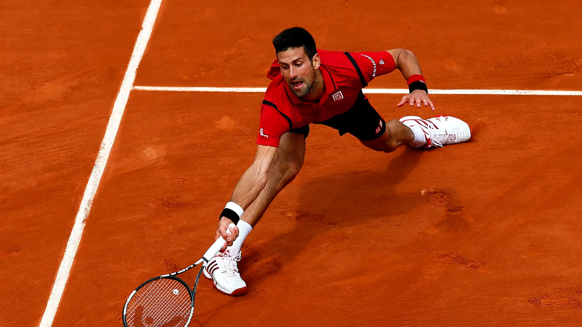 Novak Djokovic estirándose para alcanzar la pelota en Roland Garros