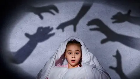 Una niña asustada en su cama Una niña asustada en su cama