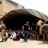 Policías iraquíes vigilan a varias personas que quedaron bajo custodia durante una operación militar en el norte de Faluya