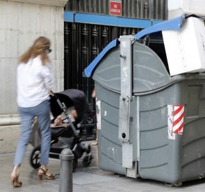Una madre con su bebé pasa junto a un contenedor Una madre con su bebé pasa junto a un contenedor