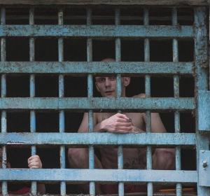 Dos prisioneros miran a través de los barrotes de su celda en la prisión Dos prisioneros miran a través de los barrotes de su celda en la prisión