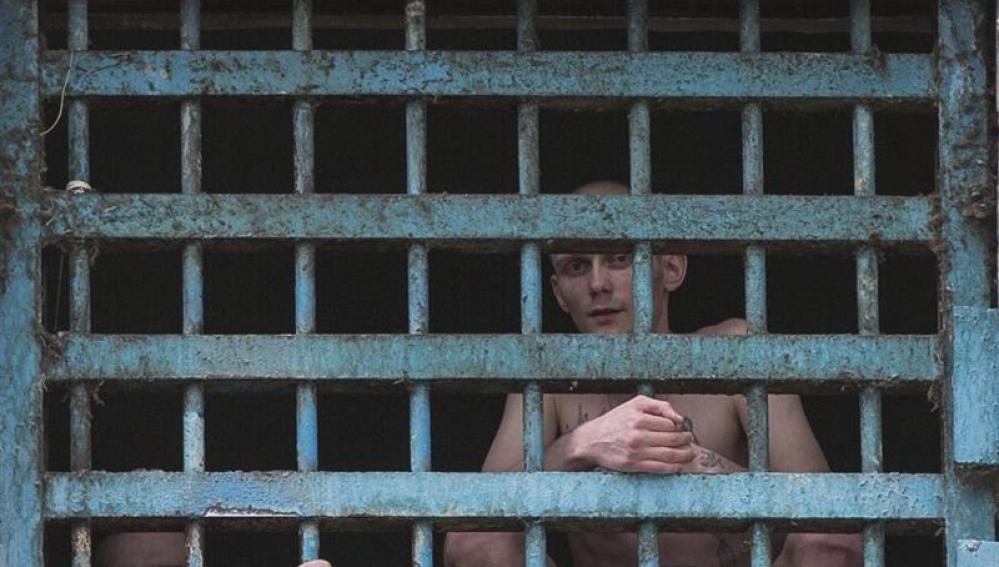 Dos prisioneros miran a través de los barrotes de su celda en la prisión