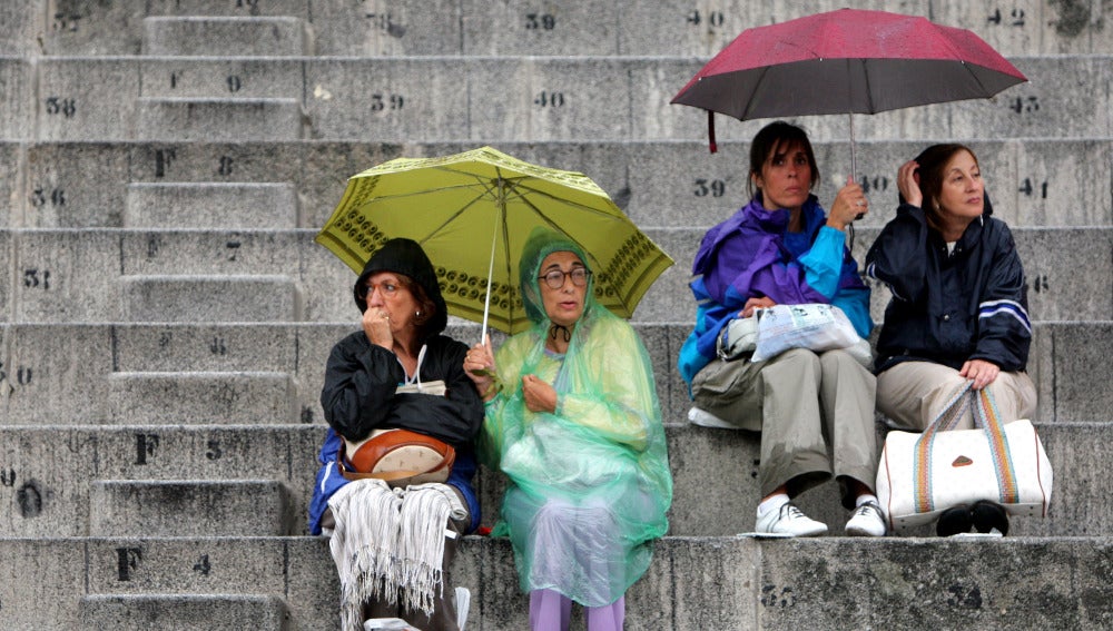 Gente protegiéndose de la lluvia con paraguas y chubasqueros