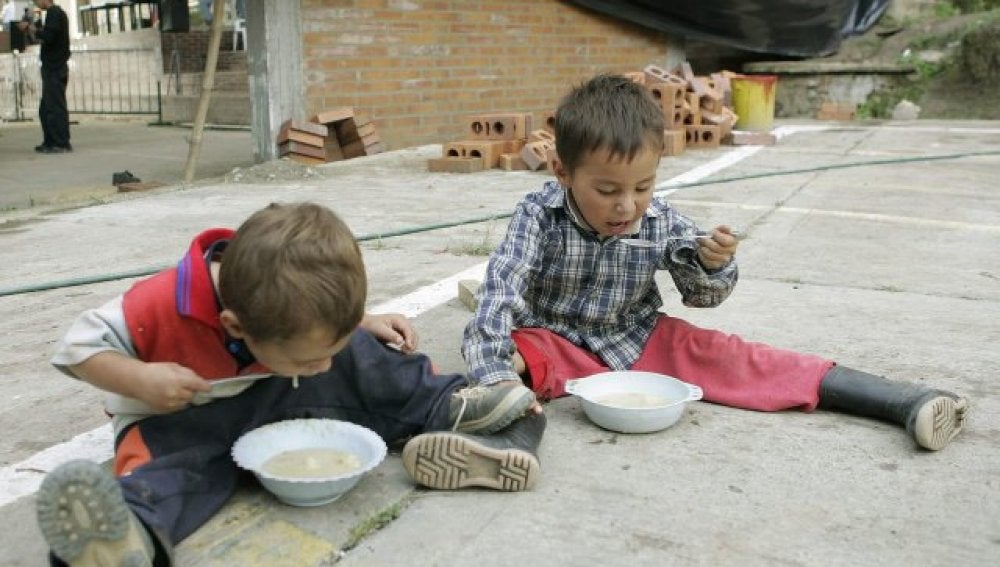 Dos niños comiendo en el suelo