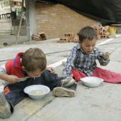 Dos niños comiendo en el suelo