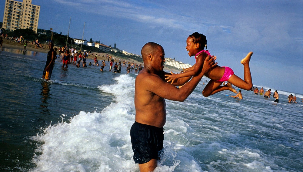 Un padre juega con su hija en la playa