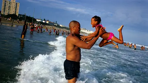 Un padre juega con su hija en la playa Un padre juega con su hija en la playa