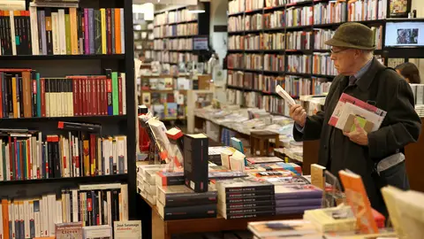 Un hombre mira un libro en una librería Un hombre mira un libro en una librería