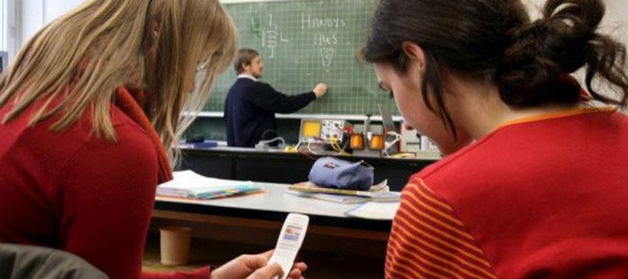 Dos alumnas utilizan sus teléfonos durante una clase Dos alumnas utilizan sus teléfonos durante una clase