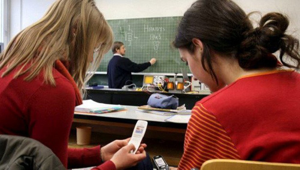 Dos alumnas utilizan sus teléfonos durante una clase