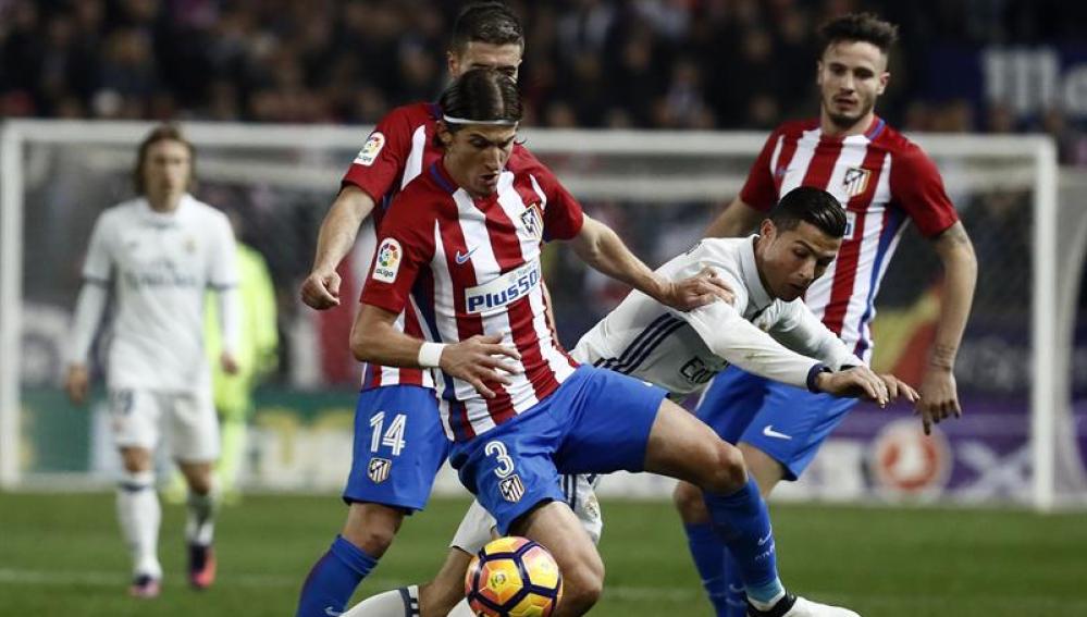 El portugués Cristiano Ronaldo (d), del Real Madrid, lucha el balón con el defensa brasielño del Atlético de Madrid Filipe Luis