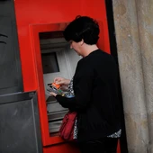Una mujer saca dinero de un cajero automático Una mujer saca dinero de un cajero automático