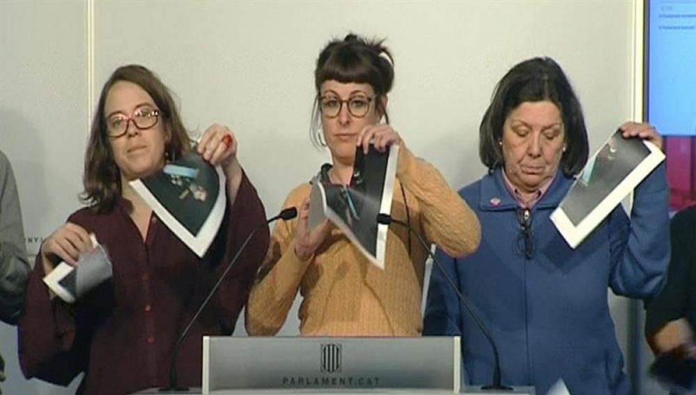 Imagen de televisión de varias diputadas de la CUP en el Parlament que rompen fotografías del Rey, durante una rueda de prensa