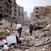 Varios sirios caminan sobre las ruinas de Alepo