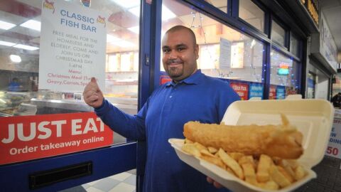 Asef posa frente a su local invitando a comer a quien lo necesite por Navidad