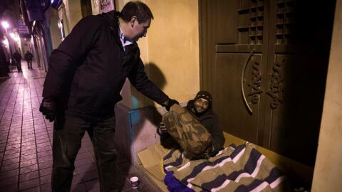 Un polic&iacute;a local entrega un saco de dormir a un 'sintecho' en Valencia