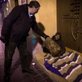 Un policía local entrega un saco de dormir a un 'sintecho' en Valencia