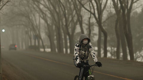 Un hombre montando en bici en China. Contaminaci&oacute;n.